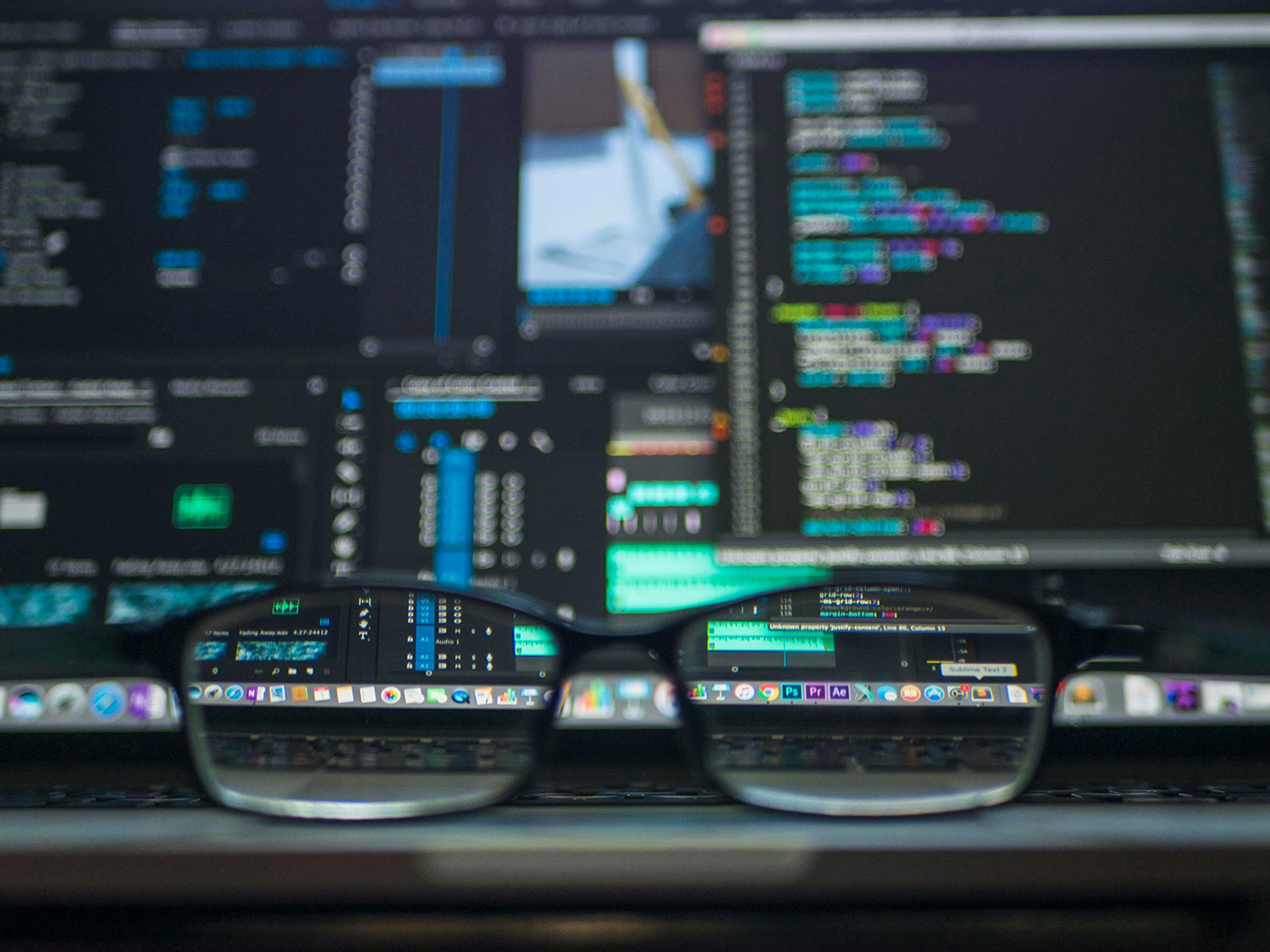 Website Developer coding with pair of glasses in front